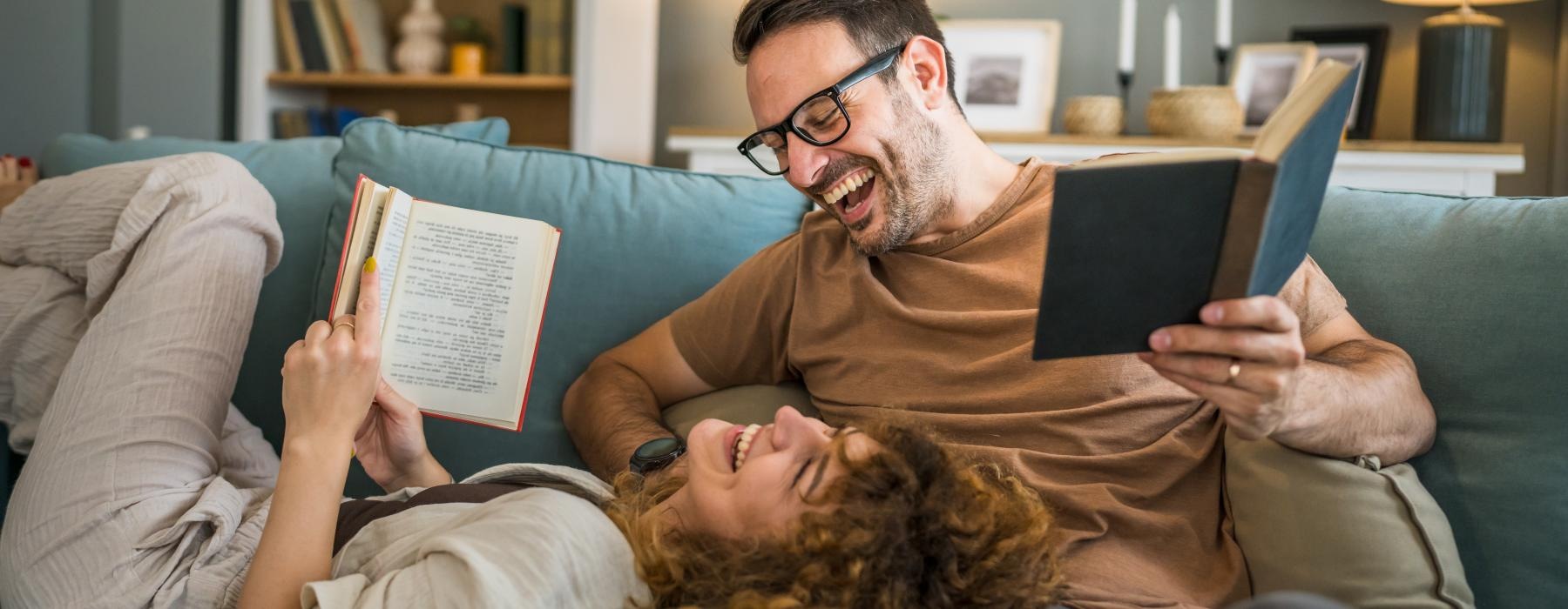 a man and woman on a couch reading books