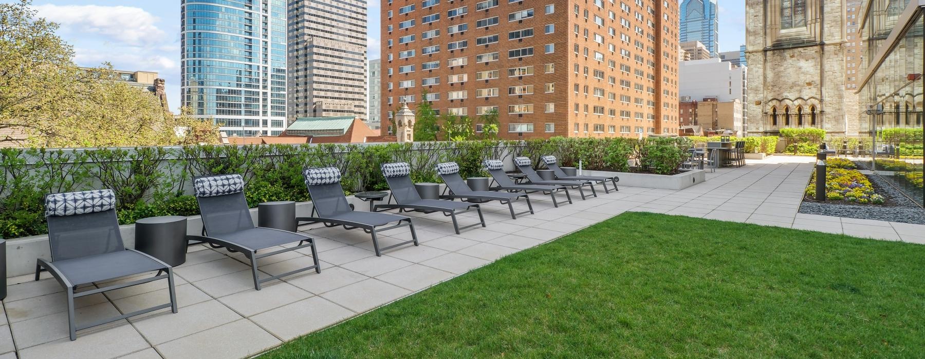 a courtyard with chairs and tables and tall buildings in the background