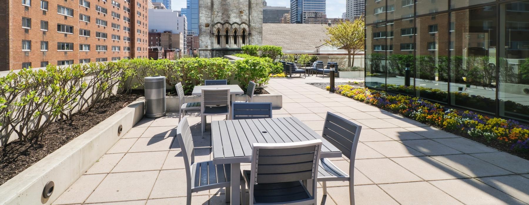 a courtyard with chairs and tables and a tall building in the background